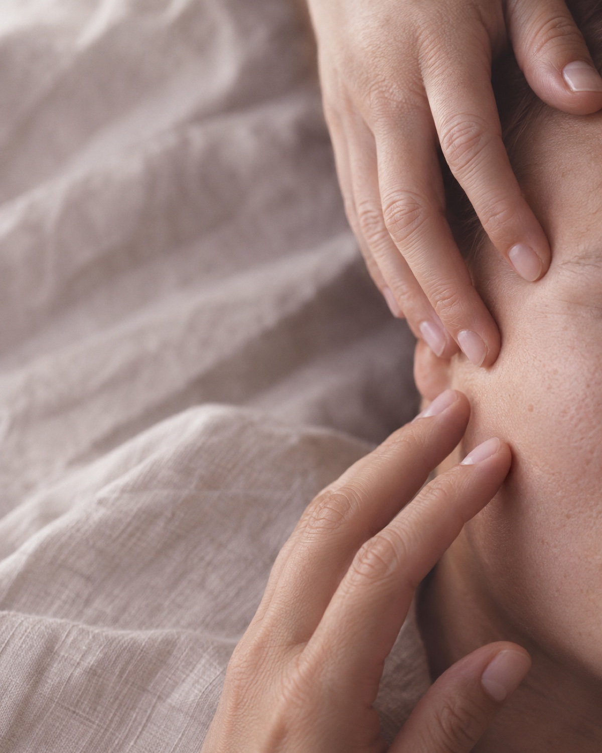 Pressions douces des mains de la praticienne sur le visage d'une personne allongée